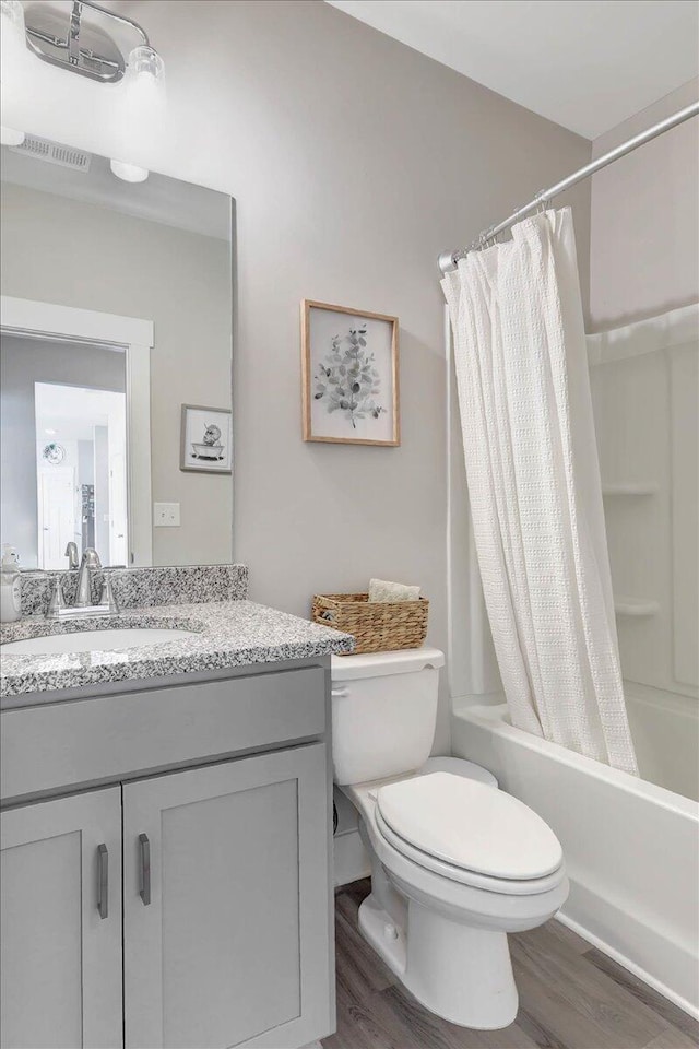 full bathroom with shower / tub combo, hardwood / wood-style floors, vanity, and toilet