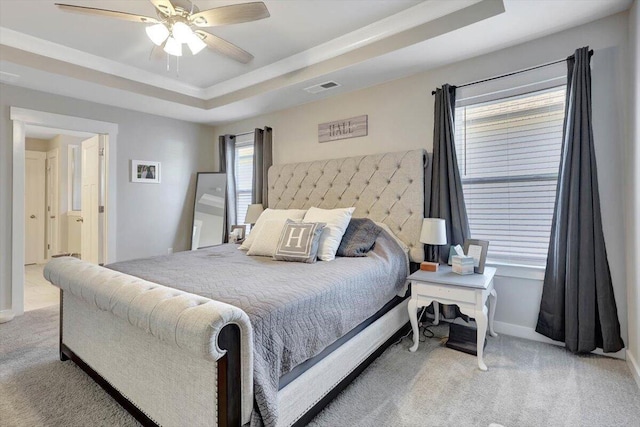 carpeted bedroom with ceiling fan and a tray ceiling