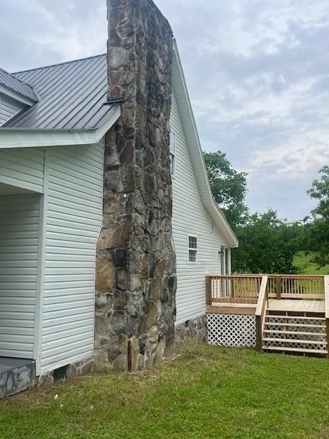 view of side of home with a deck and a yard