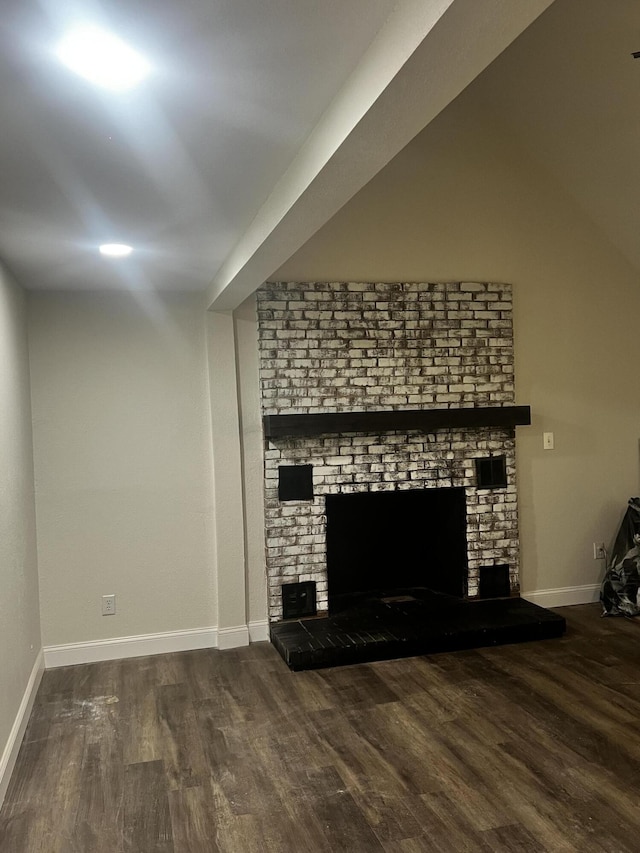 unfurnished living room featuring a brick fireplace and dark hardwood / wood-style floors