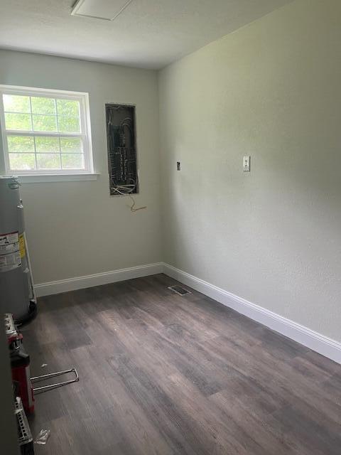 empty room with dark wood-type flooring and water heater