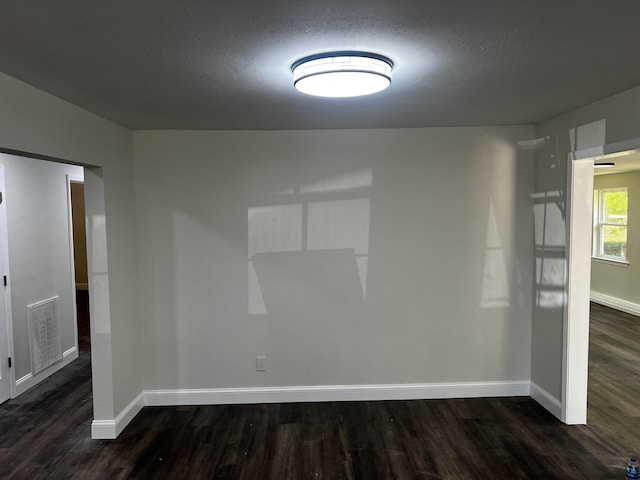 spare room with a textured ceiling and dark hardwood / wood-style floors