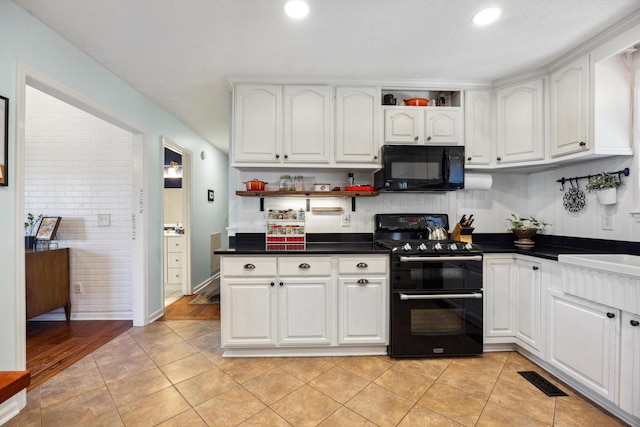 kitchen with light tile patterned floors, black appliances, and white cabinetry