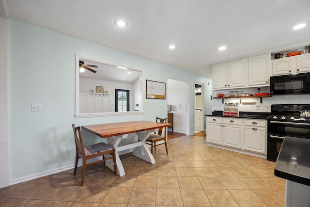 kitchen featuring vaulted ceiling, black appliances, light tile patterned floors, ceiling fan, and white cabinetry