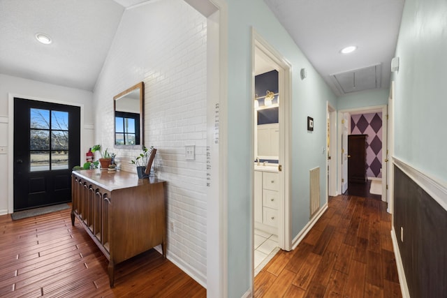 entryway featuring sink, dark wood-type flooring, vaulted ceiling, and brick wall