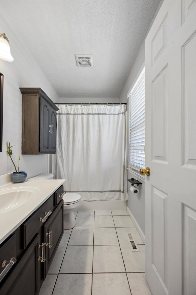 full bathroom with shower / tub combo, tile patterned flooring, toilet, vanity, and a textured ceiling