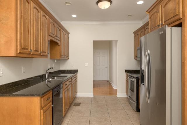 kitchen with stainless steel appliances, crown molding, light tile patterned floors, dark stone counters, and sink