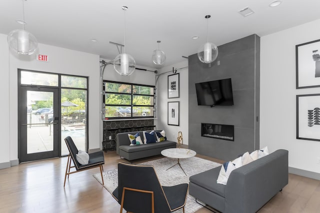 living room with a large fireplace, a healthy amount of sunlight, and light hardwood / wood-style floors