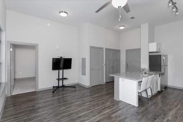 kitchen with a kitchen bar, white cabinetry, dark hardwood / wood-style floors, kitchen peninsula, and light stone counters