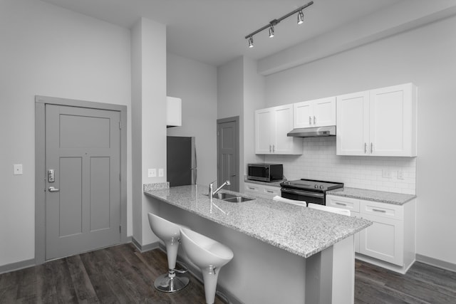 kitchen featuring kitchen peninsula, white cabinets, stainless steel appliances, and a breakfast bar area