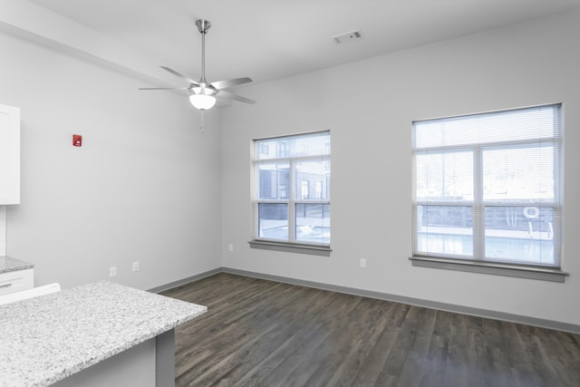 unfurnished dining area featuring plenty of natural light, ceiling fan, and dark hardwood / wood-style flooring