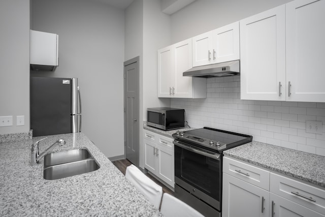 kitchen with light stone counters, sink, white cabinetry, and stainless steel appliances