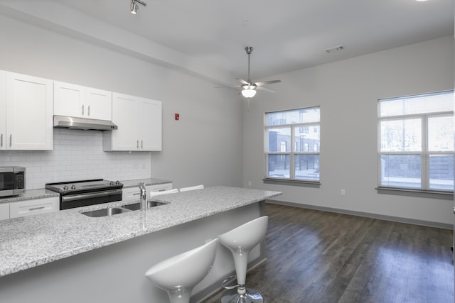 kitchen featuring light stone countertops, appliances with stainless steel finishes, white cabinetry, sink, and backsplash