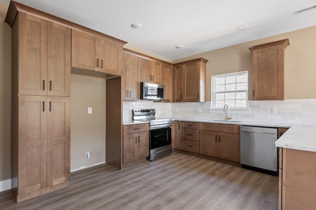 kitchen featuring brown cabinets, tasteful backsplash, stainless steel appliances, and a sink