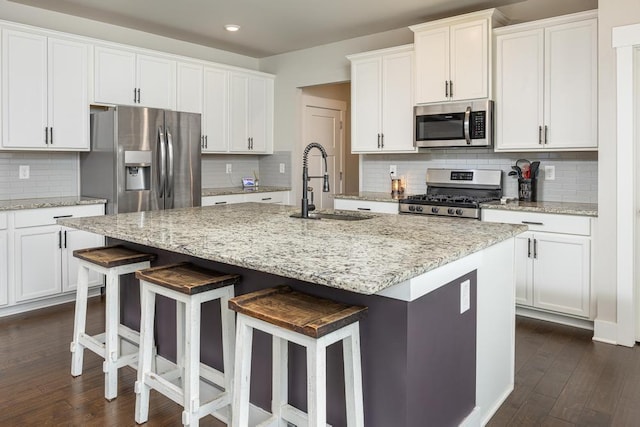 kitchen featuring a breakfast bar area, stainless steel appliances, sink, and an island with sink