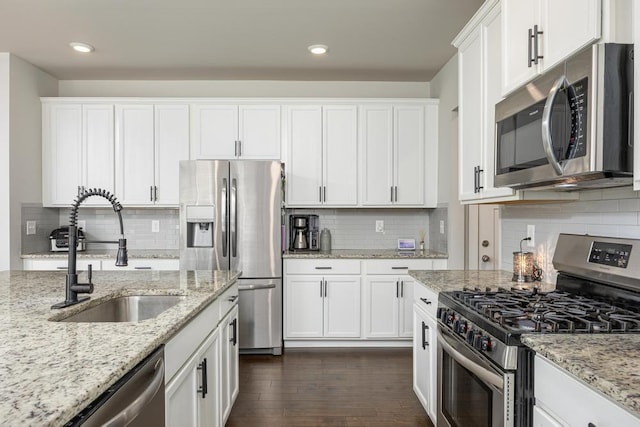 kitchen with dark hardwood / wood-style floors, sink, white cabinetry, appliances with stainless steel finishes, and light stone counters