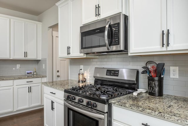 kitchen featuring light stone countertops, white cabinets, dark wood-type flooring, stainless steel appliances, and tasteful backsplash