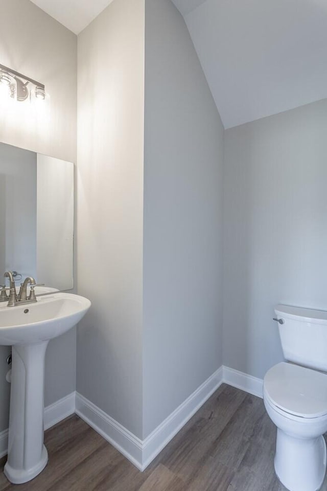 bathroom featuring sink, hardwood / wood-style floors, vaulted ceiling, and toilet