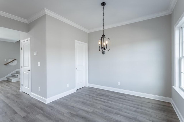 empty room with a chandelier, hardwood / wood-style floors, and ornamental molding