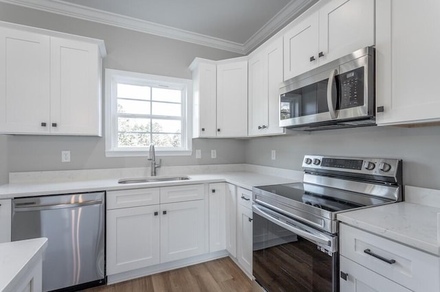 kitchen featuring light hardwood / wood-style floors, crown molding, white cabinetry, appliances with stainless steel finishes, and sink