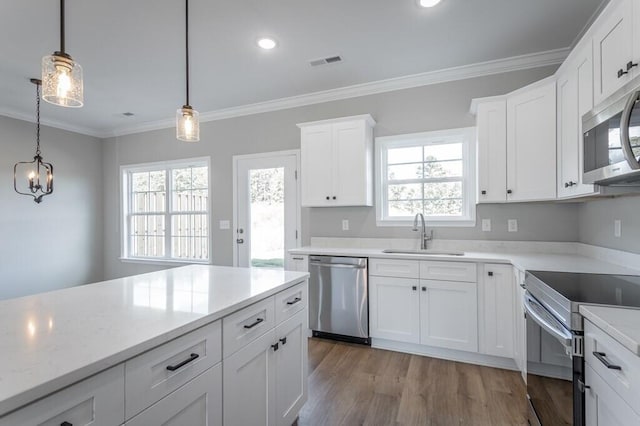 kitchen featuring stainless steel appliances, light wood-type flooring, pendant lighting, sink, and white cabinetry