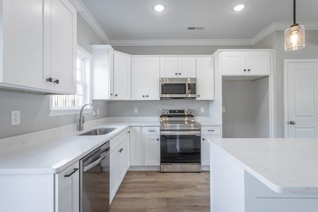 kitchen featuring stainless steel appliances, hanging light fixtures, crown molding, sink, and white cabinetry