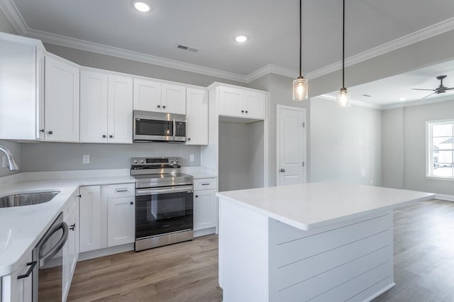 kitchen featuring pendant lighting, a center island, white cabinets, appliances with stainless steel finishes, and sink