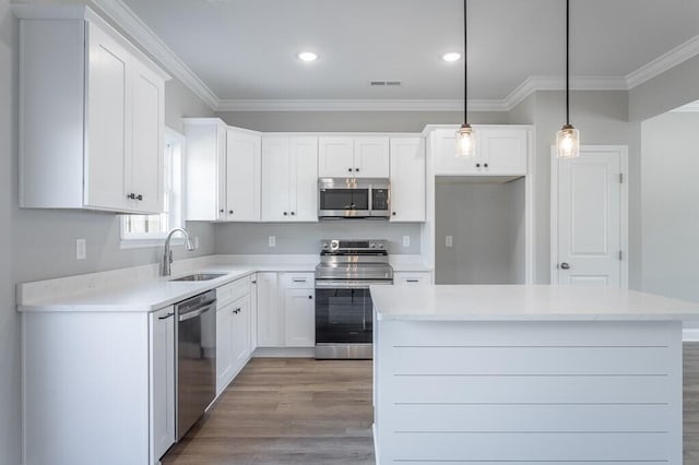 kitchen featuring sink, white cabinetry, a kitchen island, pendant lighting, and appliances with stainless steel finishes