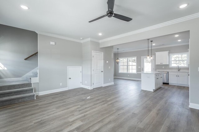 unfurnished living room featuring light hardwood / wood-style flooring, plenty of natural light, crown molding, and ceiling fan with notable chandelier