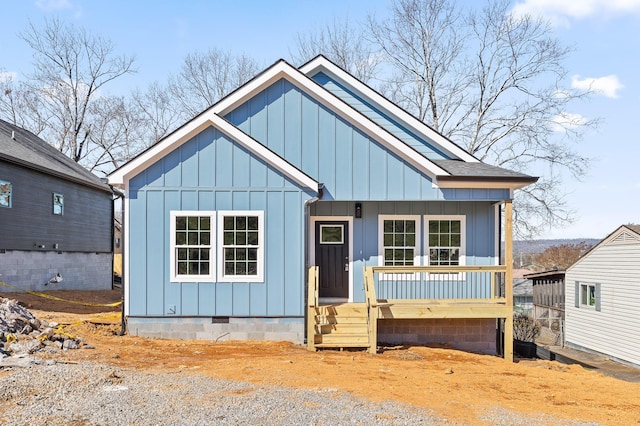 view of front facade featuring crawl space, covered porch, board and batten siding, and roof with shingles