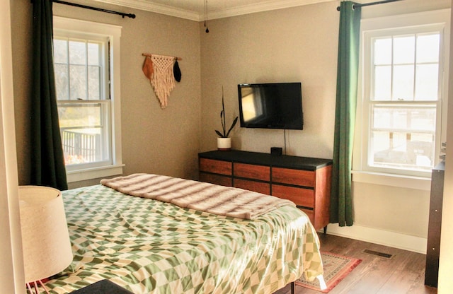 bedroom with multiple windows, ornamental molding, and hardwood / wood-style flooring