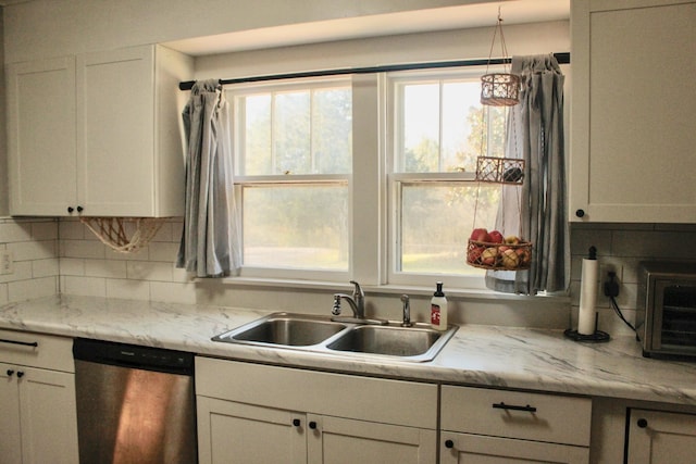 kitchen with light stone countertops, dishwasher, decorative backsplash, white cabinetry, and sink