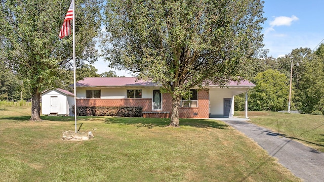 ranch-style home featuring a front yard, a carport, and a storage unit