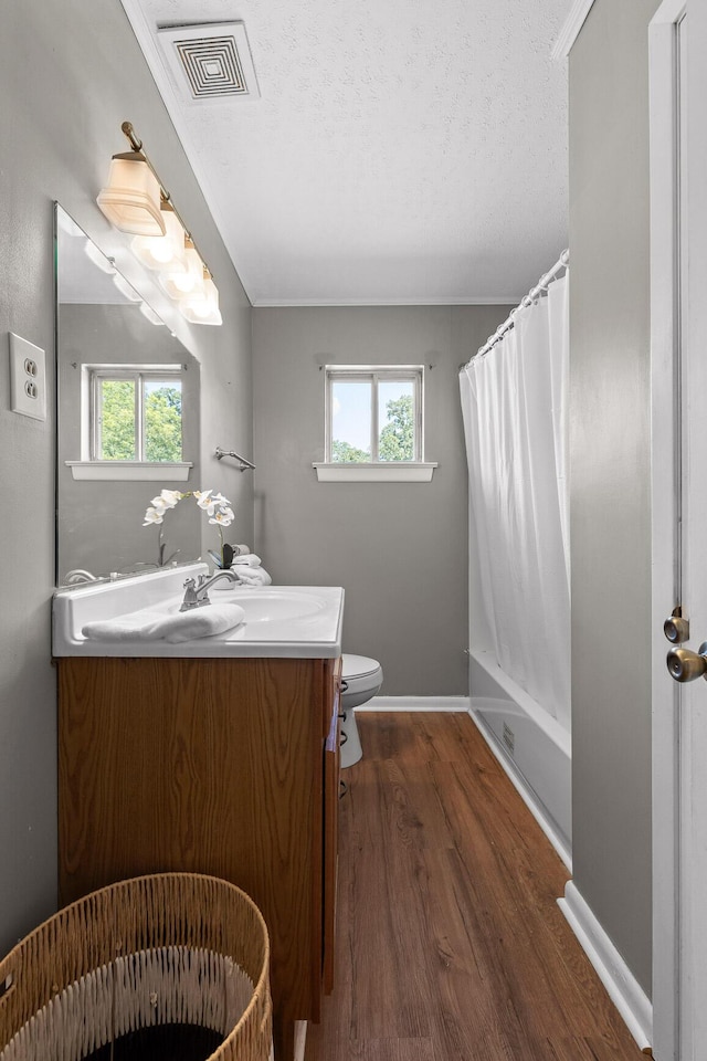 full bathroom with toilet, shower / bath combo with shower curtain, wood-type flooring, a textured ceiling, and vanity