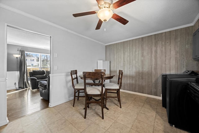 dining space featuring washer / clothes dryer, wooden walls, ceiling fan, and crown molding