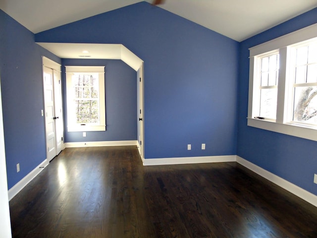 empty room with vaulted ceiling, wood finished floors, and baseboards