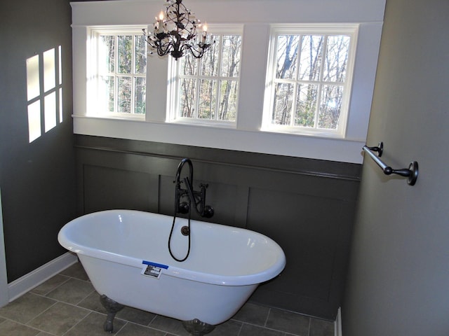 bathroom featuring a chandelier, tile patterned flooring, and a freestanding tub