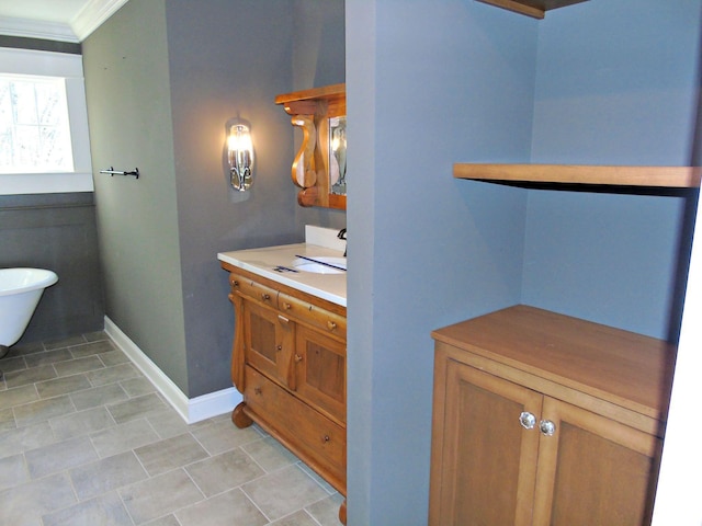 bathroom with a freestanding tub, baseboards, crown molding, and vanity