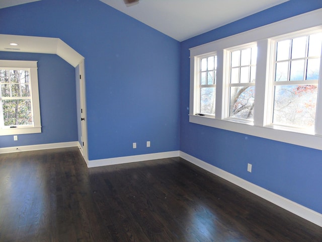 unfurnished room featuring vaulted ceiling, dark wood finished floors, and baseboards