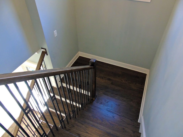 staircase featuring wood finished floors and baseboards