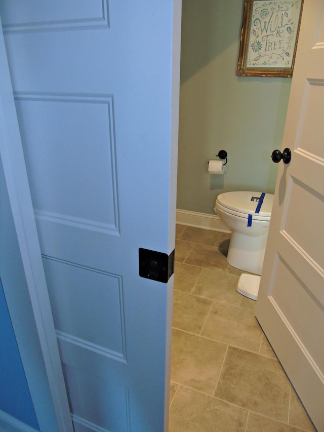 bathroom with tile patterned flooring, toilet, and baseboards