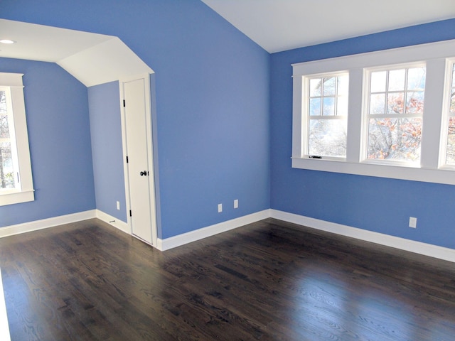 spare room featuring lofted ceiling, dark wood finished floors, and baseboards