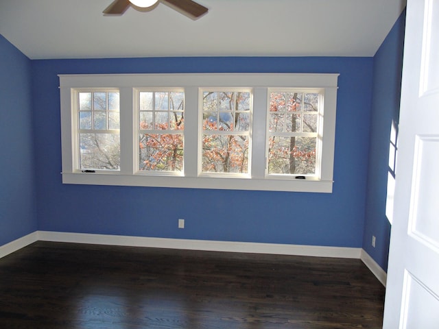 empty room featuring a ceiling fan, baseboards, and dark wood-style flooring