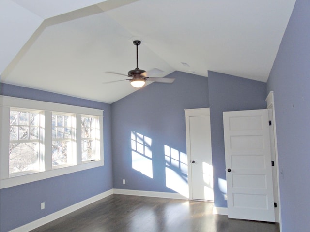 empty room featuring lofted ceiling, dark wood finished floors, a ceiling fan, and baseboards