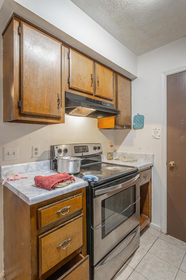 kitchen with electric stove, light tile patterned floors, and a textured ceiling