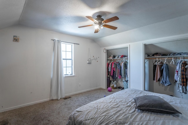 carpeted bedroom with ceiling fan, two closets, a textured ceiling, and lofted ceiling