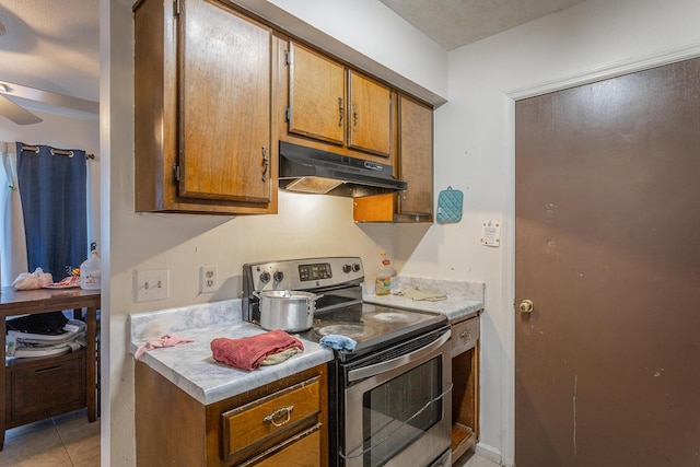 kitchen featuring ceiling fan, light tile patterned floors, and stainless steel electric range oven