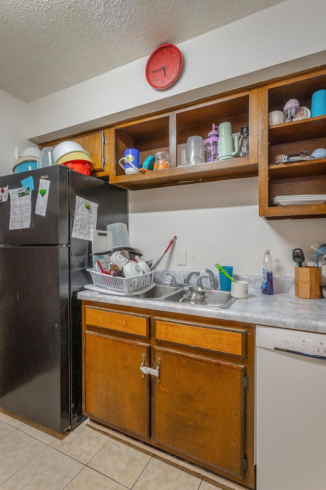 kitchen featuring black fridge, light tile patterned flooring, a textured ceiling, and dishwasher