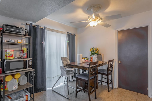 dining area featuring ceiling fan, light tile patterned floors, and a textured ceiling