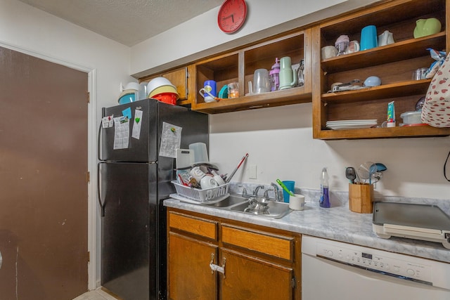 kitchen featuring white dishwasher, black refrigerator, and sink